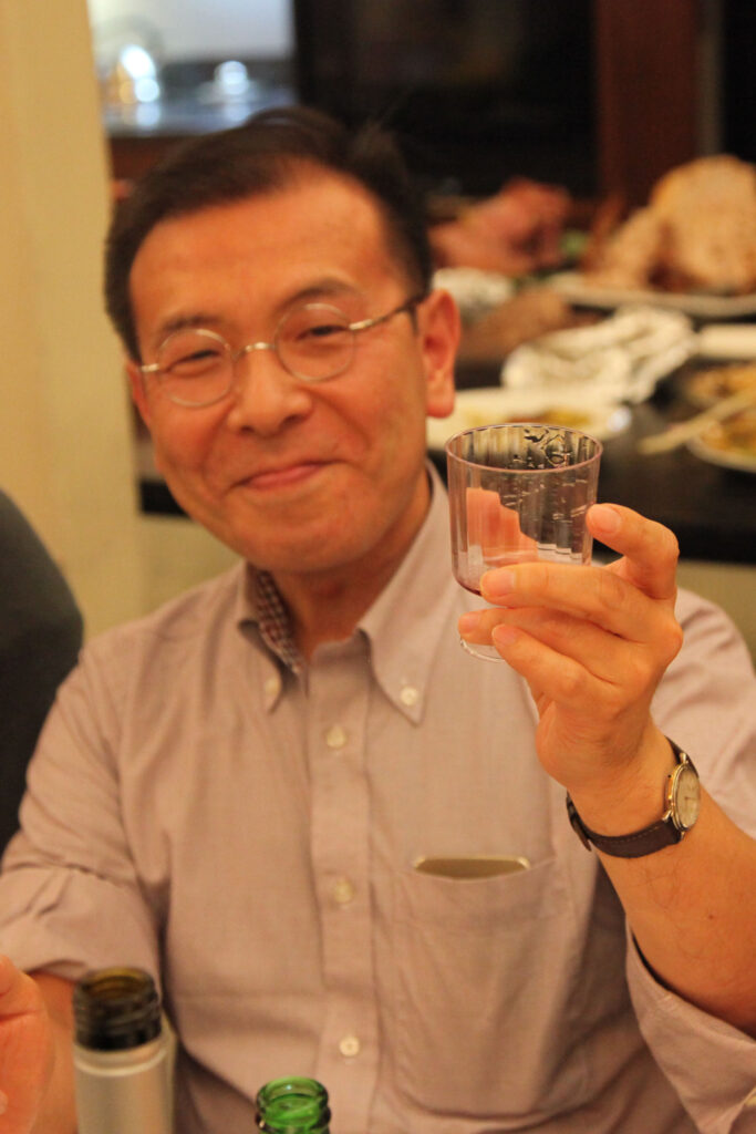 Prof. Chikamoto smiles at the camera and raises a glass