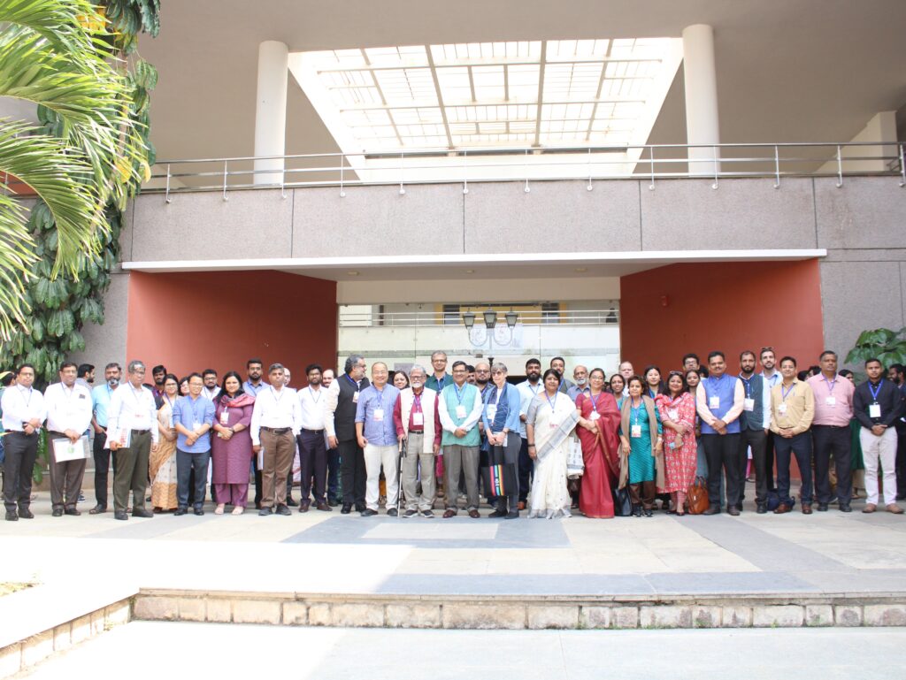 Group photo of several dozen conference attendees standing in front of a building