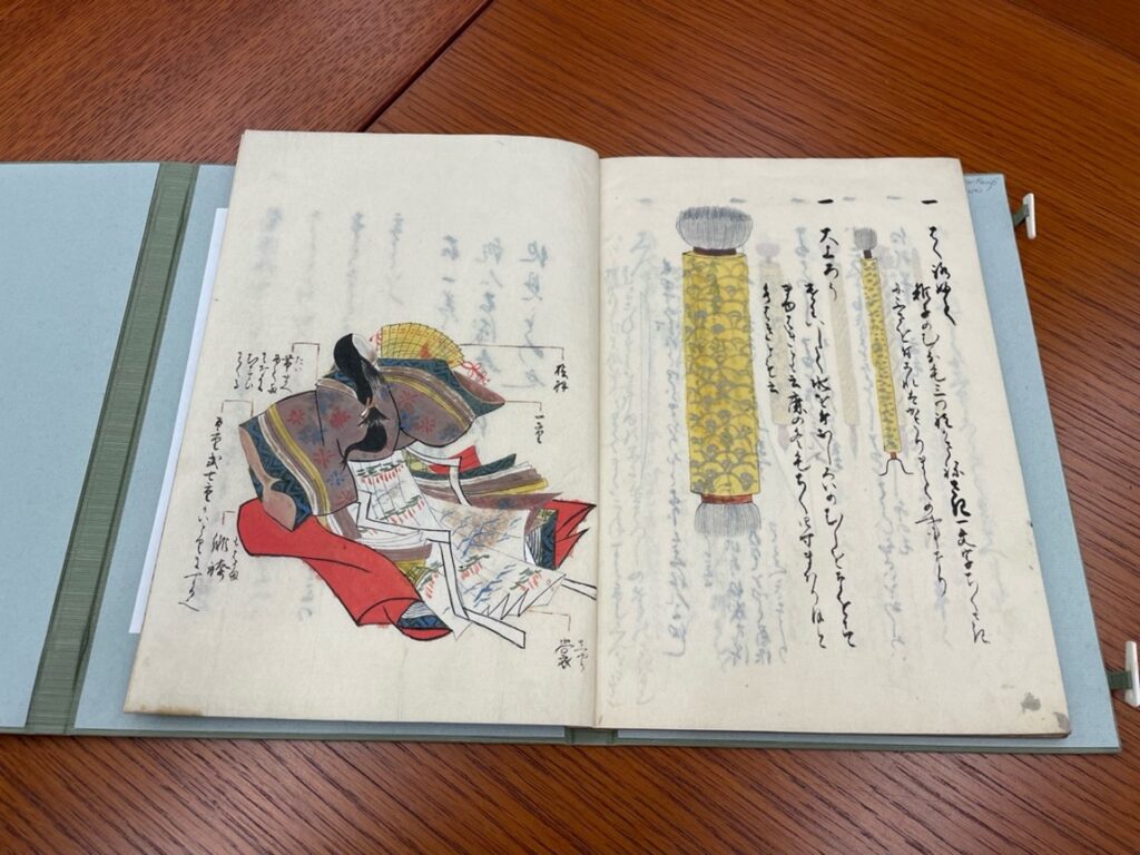 Articles of clothing appear on the left page; and on the right page, two makeup brushes with yellow handles and gray bristles are shown